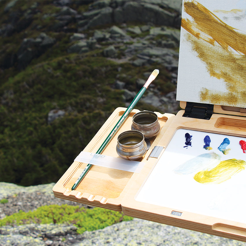 u.go Plein Air Anywhere Side Tray 4" x 8" holding a turp cup and brush while plein air landscape painting